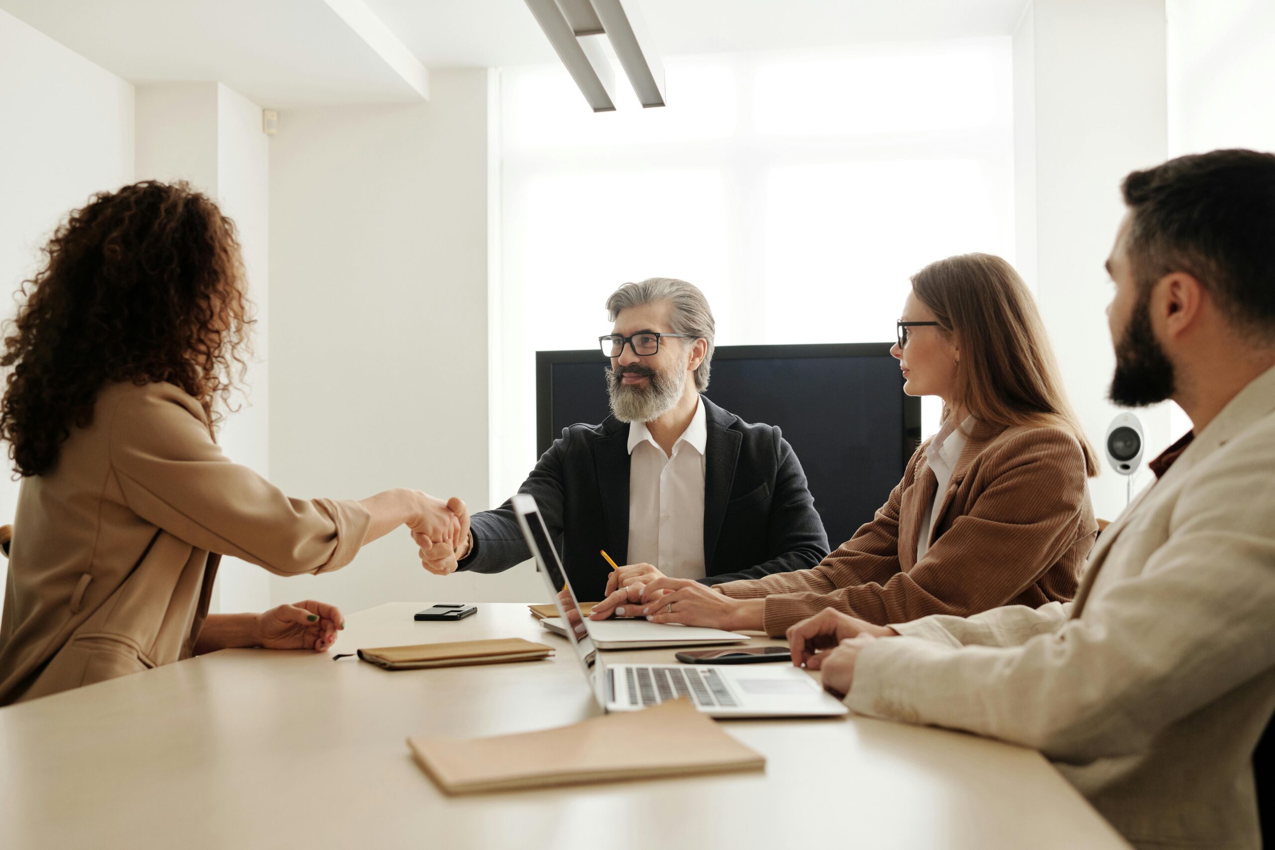 Person shaking hands with team around a table.